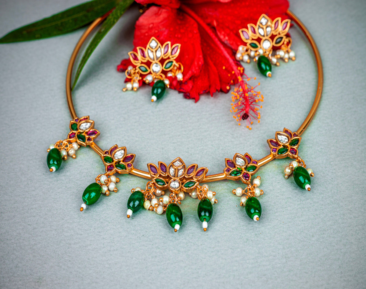 A gold pipe choker necklace with lotus design, pink stone and green beads, earrings in lotus design