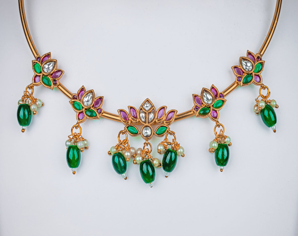A gold pipe choker necklace with lotus design, pink stone and green beads, earrings in lotus design