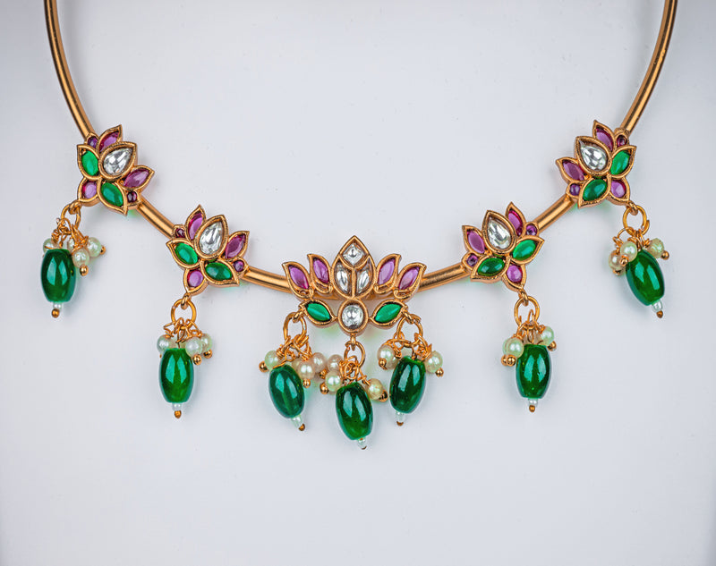 A gold pipe choker necklace with lotus design, pink stone and green beads, earrings in lotus design