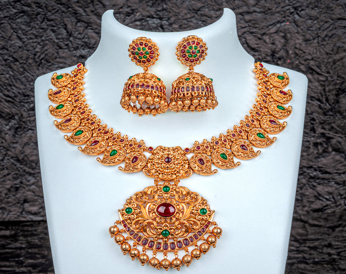 A traditional Indian necklace set in mango design with red and green kemp stone and khumkas