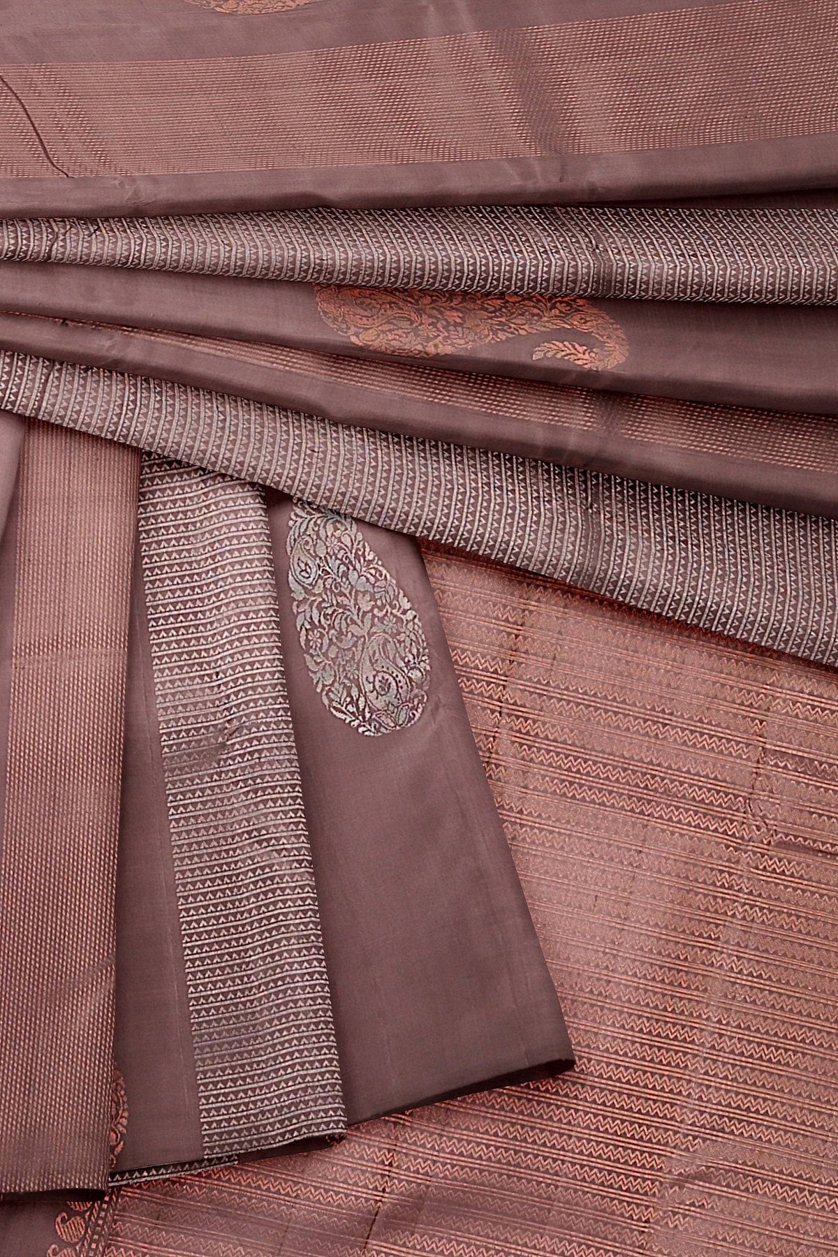 A chocolate brown kanchivaram handwoven soft silk saree in brown base and pallu, mango and geometrical motifs in silver and copper zari.