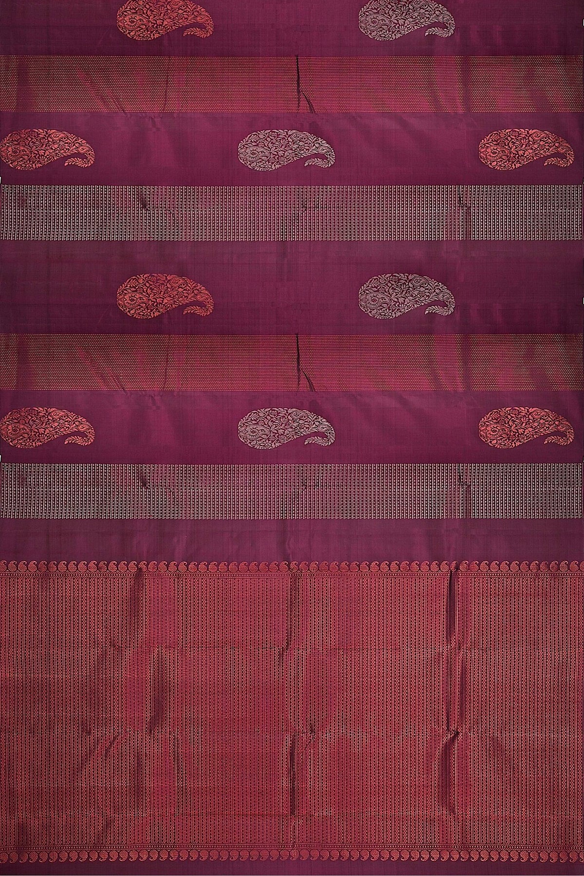 A flat representation of the handwoven soft silk saree in maroon body and pallu with paisley and geometrical motifs in silver and copper zari.