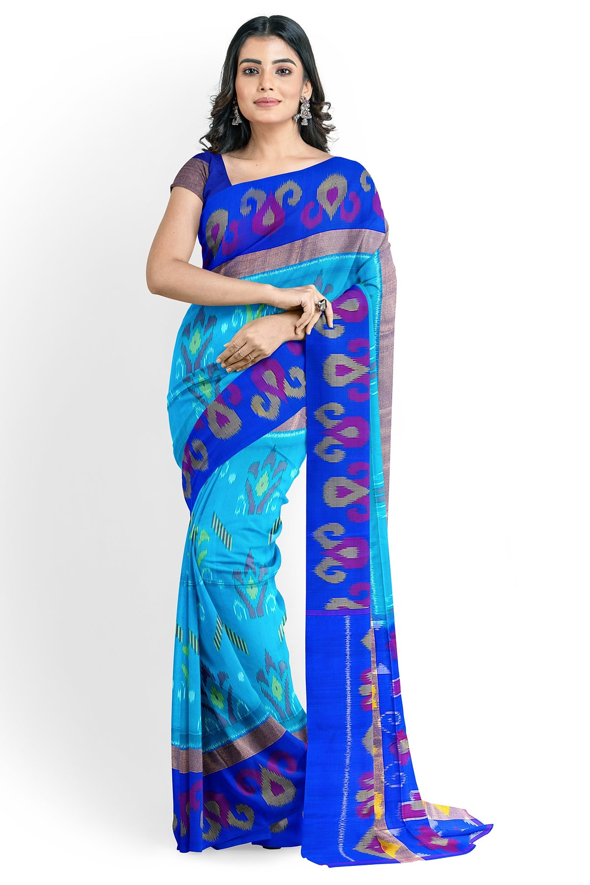 A model draped in a teal blue soft silk handloom saree with teal blue body, dark blue border & pallu. The saree is designed with geometrical Ikat motifs in half-fine zari works. The saree comes with an attached running blouse