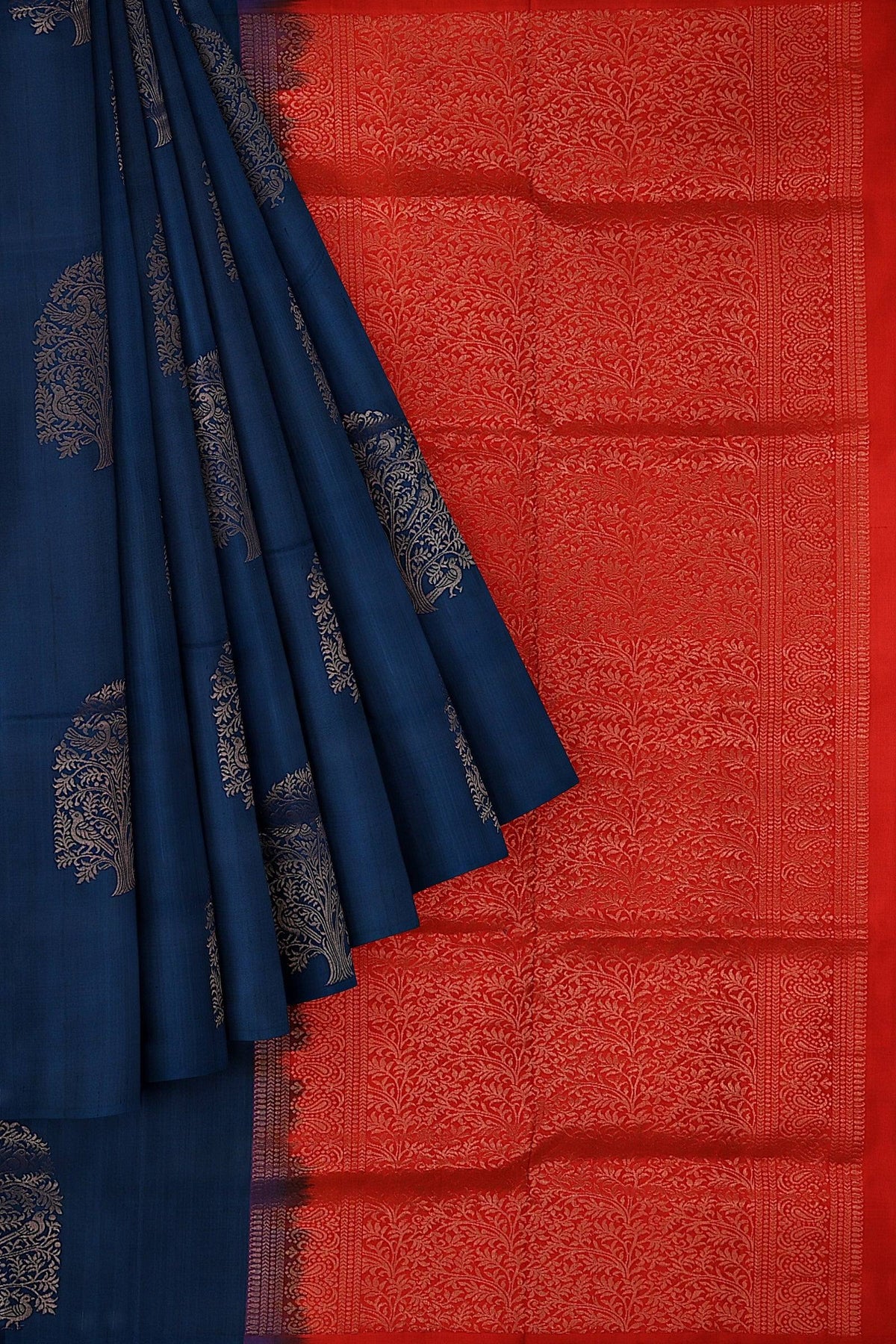 A beautiful Kanchivaram handloom saree with the body in navy blue and pallu in ruby red color with tree motifs in gold zari.