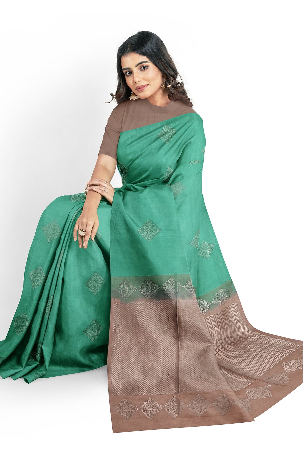 A model draped in  a unique aqua blue soft silk handloom saree with turquoise blue body and pastel brown pallu. The saree is designed with diamond motifs in silver zari works. The saree comes with an attached running blouse.